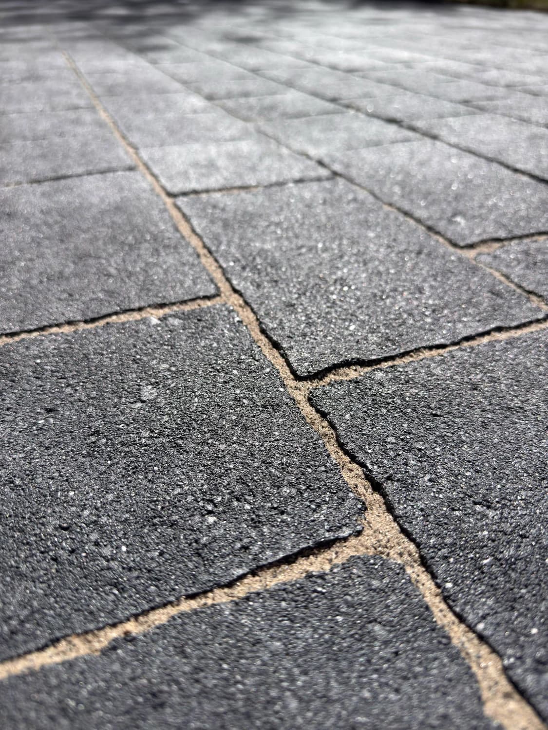 Nahaufnahme einer erneuerten, geschlossenen Fuge zwischen dunklen Pflastersteinen